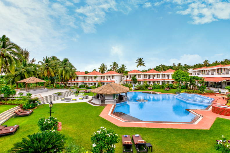 Kurort z basenem i tropikalną roślinnością. Widok na budynki.