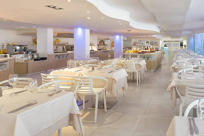Restauracja hotelowa z bufetem i nakrytymi stołami.