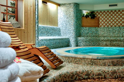 Wnętrze spa z jacuzzi, leżakami i ręcznikami.