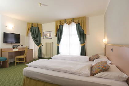 Pokój hotelowy z dwoma łóżkami, biurkiem i telewizorem.
