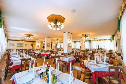 Sala restauracyjna z nakrytymi stołami i krzesłami.