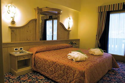 Pokój hotelowy z łóżkiem, szafką nocną i zasłonami w oknach.