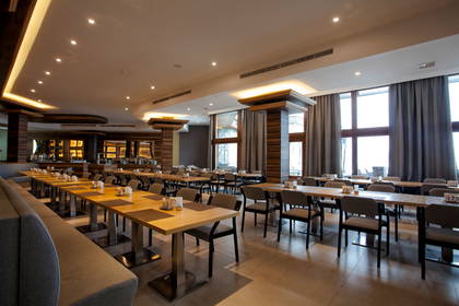 Wnętrze restauracji z oknami i nakrytymi stolikami.