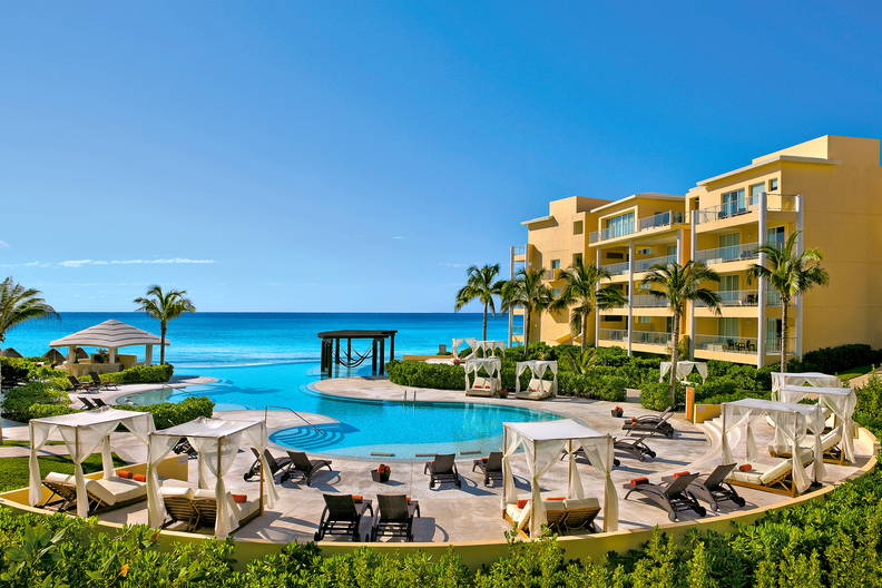 Luksusowy kurort z basenem, leżakami i widokiem na ocean.
