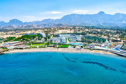 Plaża z hotelami widziana z góry, w tle góry.