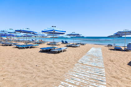 Plaża z leżakami i parasolami w biało-niebieskie paski.