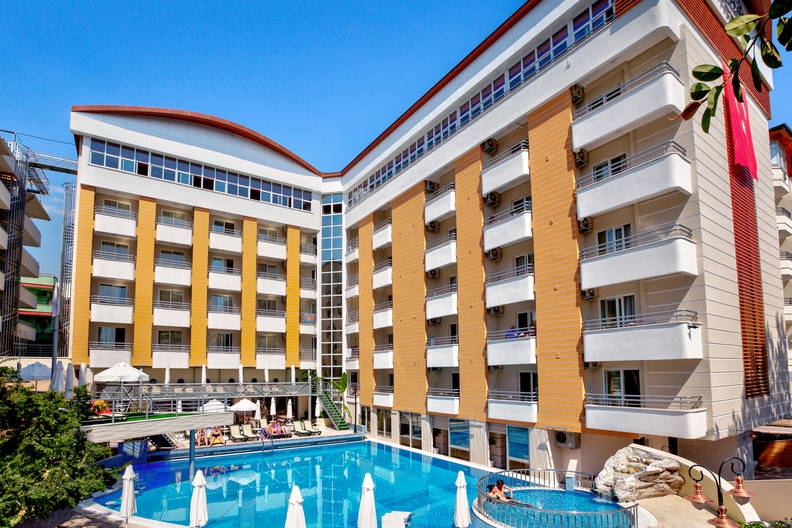 Hotel z basenem, przy którym opalają się ludzie.