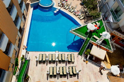 Widok z góry na basen hotelowy z leżakami i parasolami.