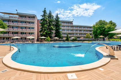 Hotel z basenem i leżakami w słoneczny dzień.