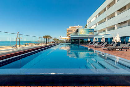Basen hotelowy z widokiem na plażę i ocean.