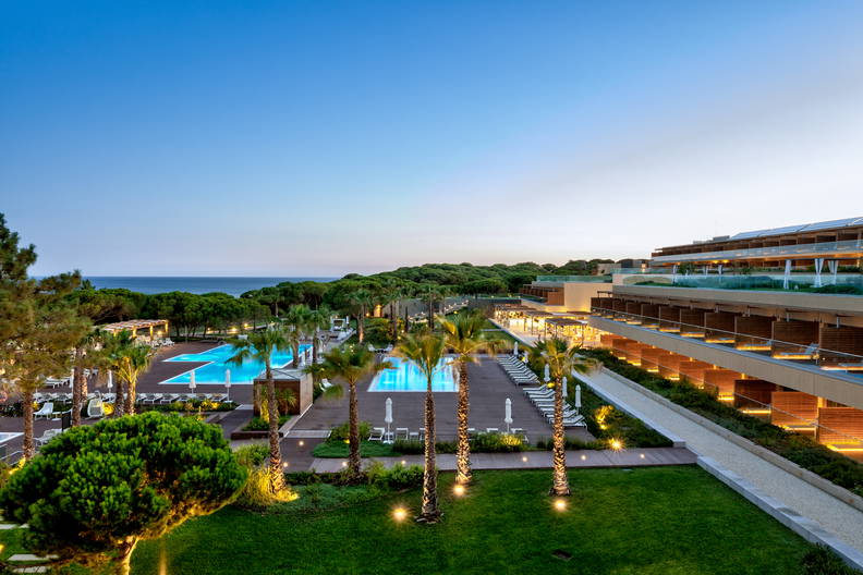 Hotel z basenami i palmami o zmierzchu, widok z góry.
