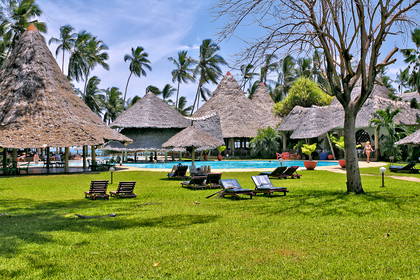 Resort z basenem, domkami krytymi strzechą i palmami.