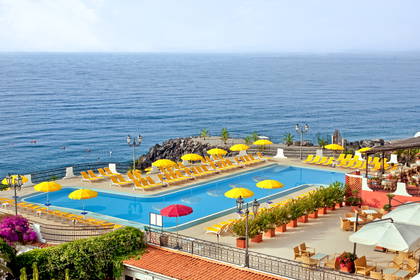 Basen z leżakami i parasolami w hotelu nad morzem.