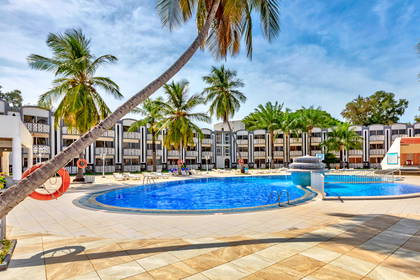Kompleks hotelowy z basenami otoczonymi palmami.