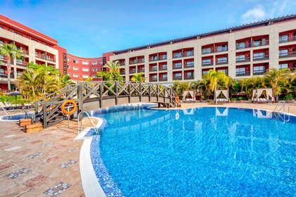 Kompleks hotelowy z basenem i drewnianą kładką.
