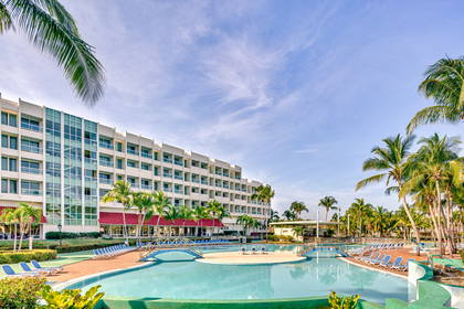 Hotel z basenem otoczonym palmami.