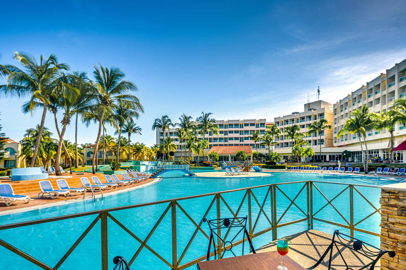 Basen w hotelu, palmy i drinki na stoliku.