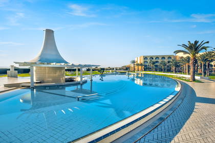 Hotel z basenem otoczony palmami.