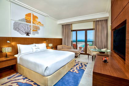 Pokój hotelowy z łóżkiem, balkonem i widokiem na ocean.