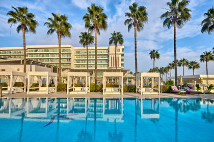 Basen z palmami i parasolami w hotelu.