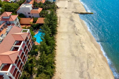Widok z lotu ptaka na plażę, hotel i basen.
