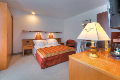 Pokój hotelowy z łóżkiem, lampą i telewizorem.