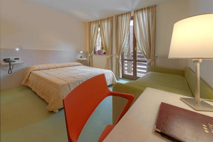 Pokój hotelowy z łóżkiem, biurkiem i balkonem.