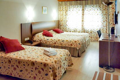 Pokój hotelowy z dwoma łóżkami i pościelą w kwiaty.