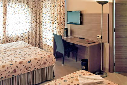 Pokój hotelowy z dwoma łóżkami, biurkiem i telewizorem.