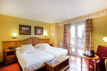 Pokój hotelowy z dwoma łóżkami, stolikiem i balkonem.