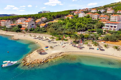 Plaża z parasolami, domami i łodzią, widok z lotu ptaka.