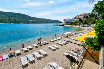 Plaża z leżakami i widokiem na morze oraz zabudowania.