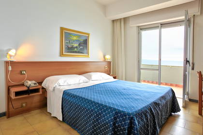 Pokój hotelowy z balkonem i widokiem na morze.
