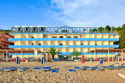 Hotel na plaży z leżakami i parasolami przeciwsłonecznymi.