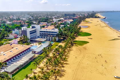 Hotel przy piaszczystej plaży z widokiem na ocean i miasto. Zdjęcie z lotu ptaka.