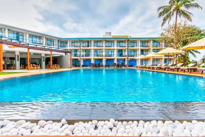 Basen z leżakami i palmami przy hotelu.