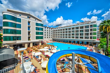 Kompleks hotelowy z basenem, zjeżdżalnią i wypoczywającymi gośćmi.