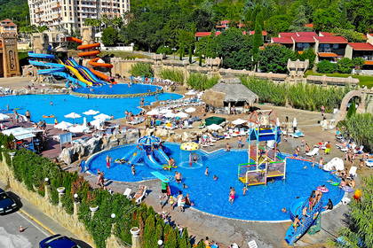 Widok z góry na aquapark: baseny, zjeżdżalnie i kąpiący się ludzie.