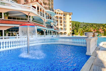 Kompleks hotelowy z basenem i fontanną.