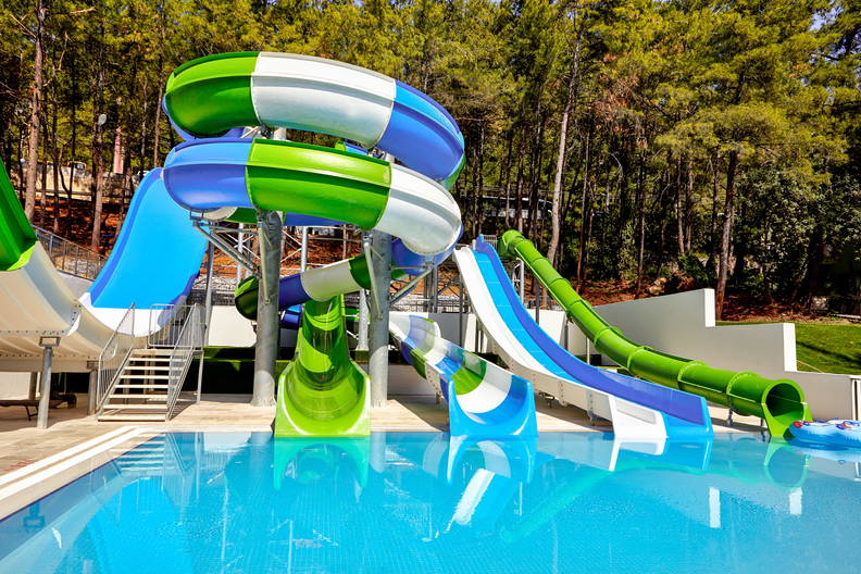 Wodne zjeżdżalnie odbijające się w tafli basenu w parku wodnym.