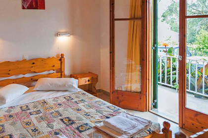 Pokój hotelowy z łóżkiem, szafkami nocnymi i balkonem.