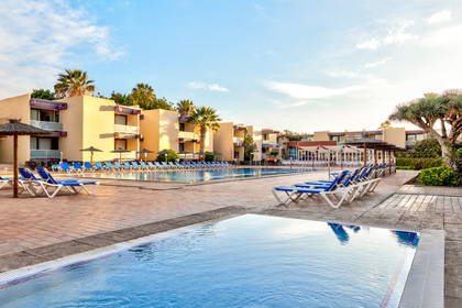 Kompleks hotelowy z basenami i leżakami do opalania.