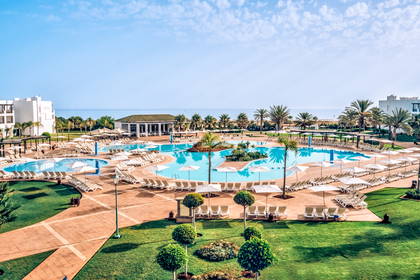 Resort z basenami, leżakami i palmami, widok z góry.