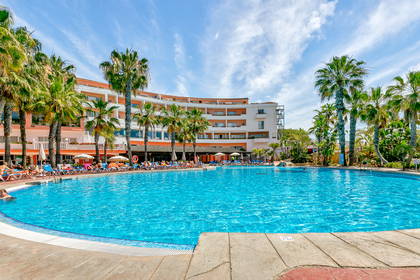 Hotel z basenem otoczonym palmami.