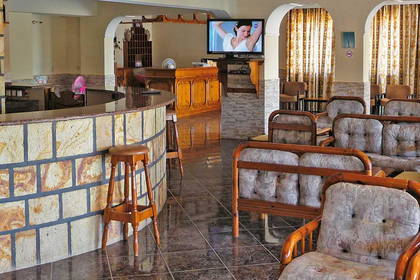 Lobby hotelowe z barem, stolikami i telewizorem.