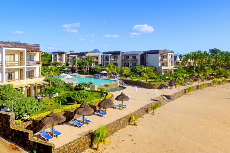 Luksusowy kurort z basenem, plażą i palmami.