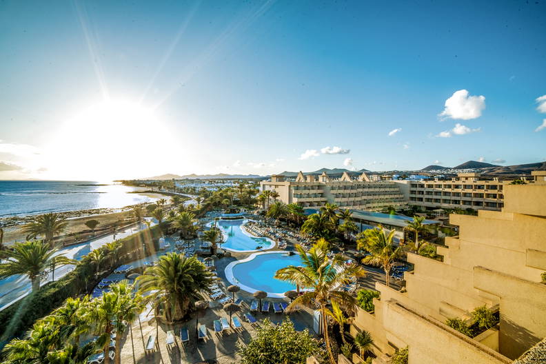 Hotel z basenami przy plaży w słoneczny dzień.