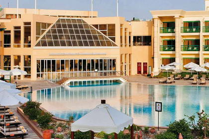 Panorama hotelu z basenem, leżakami i barem przy basenie.