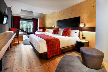Pokój hotelowy z dużym łóżkiem, rozkładaną sofą i ścianami wyłożonymi drewnem.