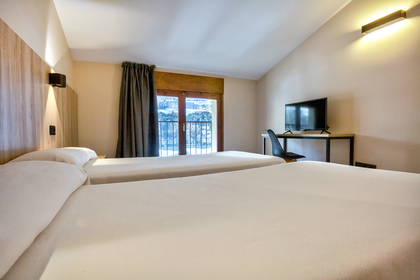 Pokój hotelowy z dwoma łóżkami, telewizorem i balkonem.